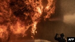 Un pompier încearcă să oprească un incendiu la o instalație industrială avariată în urma unei lovituri aeriene, în regiunea Kiev, pe fondul invaziei ruse.