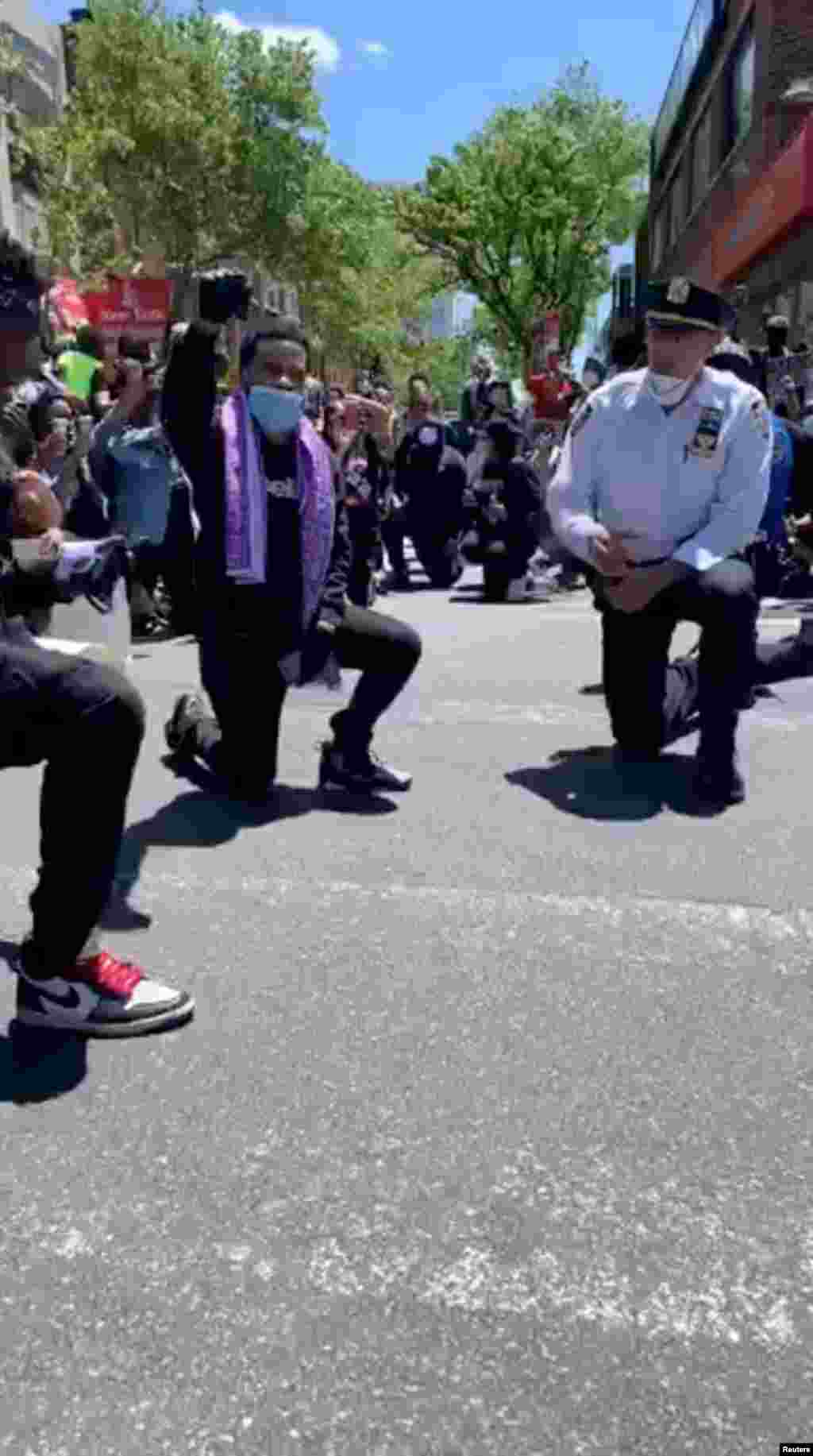 Njujorški policajci kleče zajedno s demonstrantima nakon što su ih demonstranti zatražili da to učine. Queens, New York.