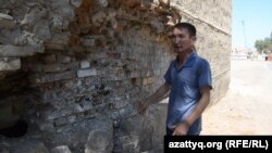Житель Кызылорды Серикбай Сейдильдаев показывает на обрушившуюся часть стены в здании общежития, в котором проживает. Кызылорда, 4 августа 2015 года.
