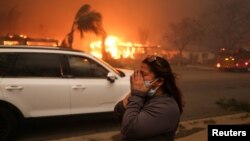 Жена се евакуира на фона на пожара в района на Лос Анджелис, в Алтадина, Калифорния, САЩ, 8 януари 2025 г.