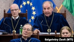 A ma már köztársasági elnök Sulyok Tamás elnök (felül j) az Alkotmánybíróság nyilvános ülését követően egy 2017. október 17-i határozathirdetésen. Mellette Varga Zs. András (ma már Kúria-elnök), elöl Pokol Béla és Szívós Mária alkotmánybírók.