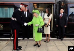 Regina Elisabeta a II-a sosind la Runcorn Station, în Anglia, în compania Ducesei de Sussex, Meghan, în iune 2018.