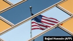 Flamuri i Shteteve të Bashkuara i pasqyruar në dritaret e një ambasade amerikane. Fotografi nga arkivi.