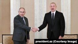 Ilham Aliev (dreapta) și Nikol Pașinian își strâng mâinile la întâlnirea de la Abu Dhabi, 10 iulie 2025.