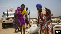 Žene nose vreću sa žitaricama koje je podijelio Međunarodni odbor Crvenog križa, Južni Sudan, 2017.
