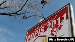 Egy nő sétál el az „Ingyenes népszámlálás 2011” feliratú plakát előtt Montenegró fővárosában, Podgoricában, 2011 áprilisában