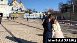 Нова брачна двојка позира на плоштадот пред киевската катедрала Свети Михаил, 12 февруари 2022 година. 