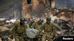 Spasioci nose telo žrtve cunamija u opustošenom gradu Otcući, 14. mart 2011.