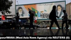 Ljudi prolaze pored murala sa slikom iranskog vrhovnog vođe, ajatolaha Alija Hamneija, na ulici, u ranim jutarnjim satima primirja, u Teheranu, Iran, 24. juna 2025.