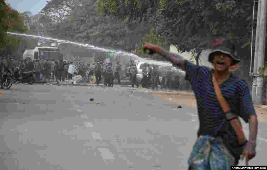 Demonstrant pokazuje na policiju koja puca iz vodenih topova tokom protesta protiv vojnog puča u Mandalaju, 20. februar.