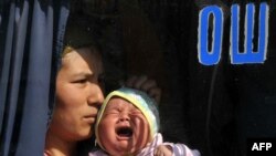 Женщина с ребенком выглядывает из окна автобуса с надписью "Ош". 23 июня 2010 года.