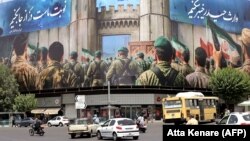 Automjetet kalojnë pranë një pankarte të madhe në Sheshin e Revolucionit të Teheranit, teksa duket se po zbatohet armëpushimi.