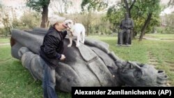 Egy moszkvai férfi a bulldogjával játszik a KGB-t megalapító Feliksz Dzerzsinszkij szobrán egy belvárosi parkban. Moszkva, 1991. augusztus 31. 