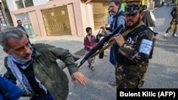 A member of the Taliban special forces pushes a journalist (left) covering a demonstration by women protesters outside a school in Kabul on September 30.