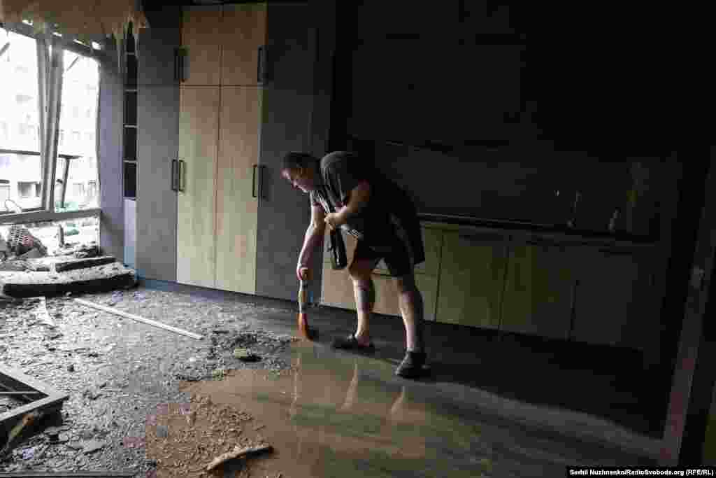 Un bărbat face curățenie în interiorul clădirii avariate din cartierul Șevcenkivski.