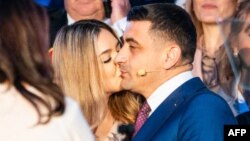 Съпругата на ултранационалиста Джордже Симион го целува след обявяването на първите екзитполове на втория тур на президентските избори в Румъния. Симион, който беше смятан за фаворит след първия тур, загуби от прозападния математик и кмет на Букурещ - Никушор Дан.