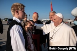 Semjén Zsolt miniszterelnök-helyettes, Erdő Péter bíboros és népviseletbe öltözött gyerekek köszöntik a pápát 2021. szeptember 12-én