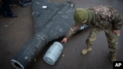 Un militar ucrainean, examinând o dronă rusească Shahed cu bombă termobarică, doborâtă de Ucraina