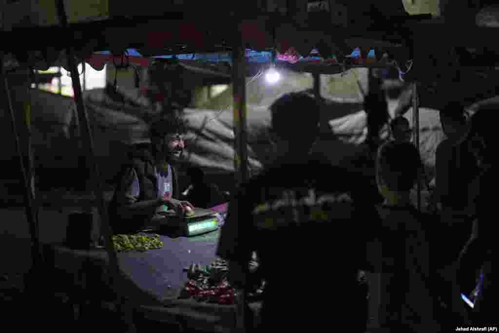 Një shitës ambulant palestinez duke buzëqeshur para konsumatorëve të tij, teksa po shiste perime pranë plazhit, në një kamp për të zhvendosurit në portin e Qytetit të Gazës, më 2 shtator 2025.