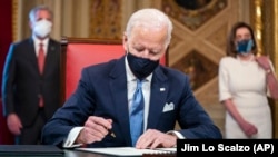 Joe Biden elnök a beiktatási dokumentumot és kormányzati tisztviselők jelölési dokumentumait írja alá 2020. január 20-án.