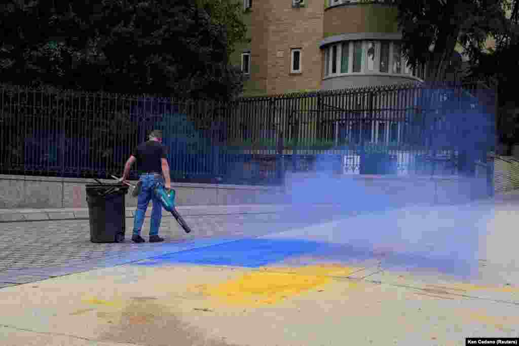 Egy férfi takarítja el az ukrán zászló színeit a járdáról a washingtoni orosz nagykövetség előtt 2025 augusztusában