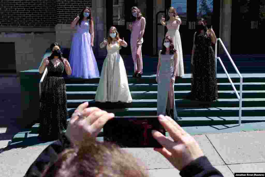 Ученички од Централната католичка гимназија во Алентаун во матурски фустани одржуваат физичка оддалеченост додека нивните мајки ги фотографираат, откако нивната матурска вечер беше откажана во Алентаун, Пенсилванија, САД. 14 мај 2020 година.