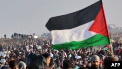 Një person duke valëvitur një flamur palestinez mes një grumbulli njerëzish në Gazë, më 27 janar 2025.