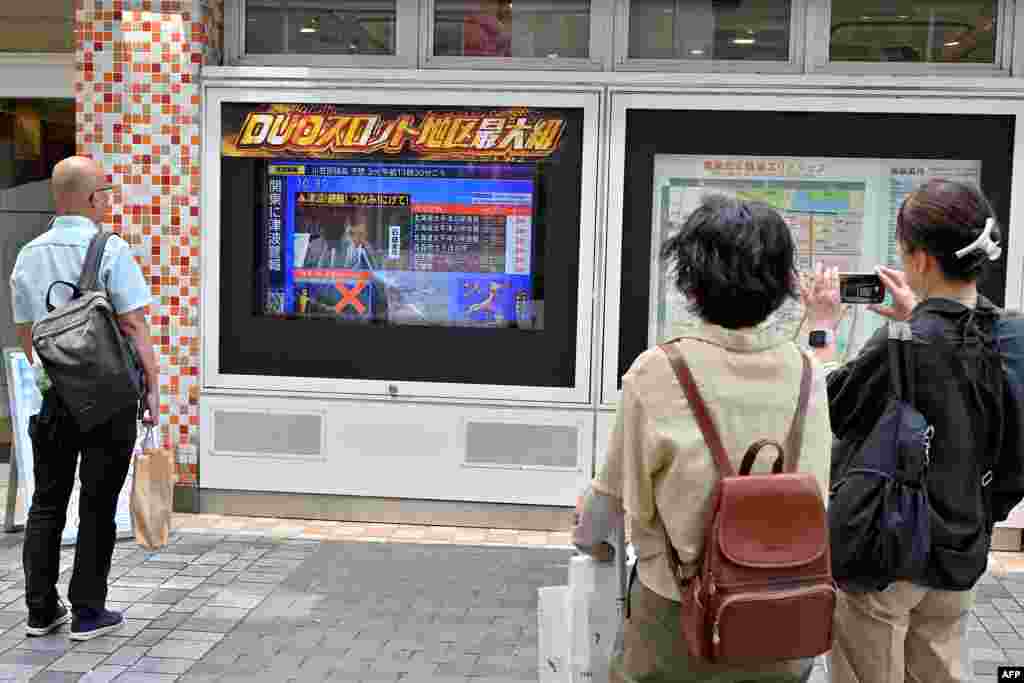 Prolaznici u Tokiju prate vijesti nakon upozorenja na cunami, Japan, 30. jula 2025.