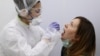 RUSSIA -- A health worker wearing protective gear takes a swab from a woman to test for the coronavirus disease (COVID-19) at Gemotest laboratory in Moscow, April 6, 2020