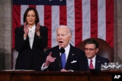 ჰარისი დგას და ტაშს უკრავს, ხოლო წარმომადგენელთა პალატის სპიკერი მაიკ ჯონსონი (რესპუბლიკელი ლუიზიანის შტატიდან) უსმენს ბაიდენს, როცა ის სიტყვით გამოდის კაპიტოლიუმში, კონგრესის ერთობლივ სესიაზე, 2024 წლის 7 მარტს.