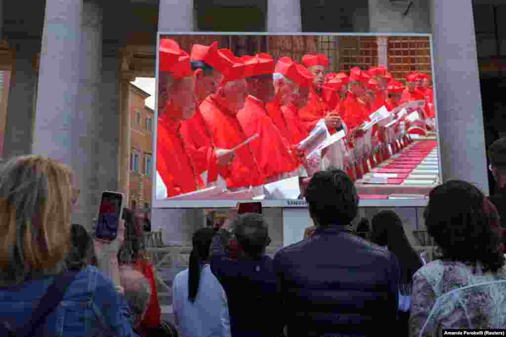 Njerëz të mbledhur në Sheshin e Shën Pjetrit duke shikuar një ekran që shfaqte kardinalët brenda Kishëzës Sistina, më 7 maj.