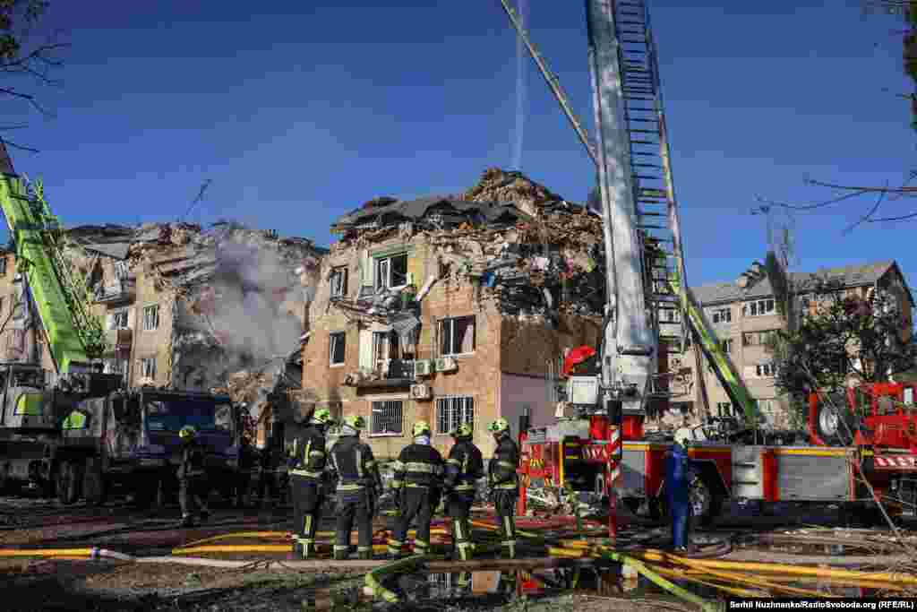 Сотрудники МЧС использовали выдвижные лестницы и специализированное оборудование, чтобы добраться до верхних этажей частично разрушенного здания в Дарницком районе Киева 