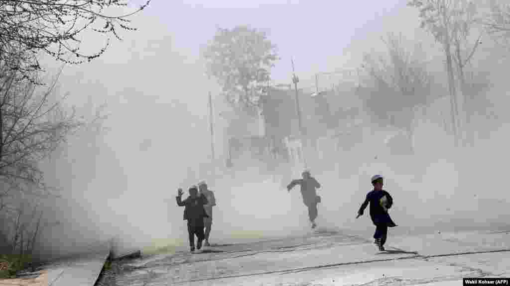 Afganistanska djeca trče kroz oblak prašine dok vojni helikopter slijeće u Zelenu zonu u Kabulu.