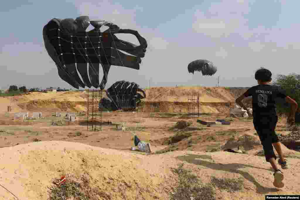 Palestinski dječak trči dok se pomoć iz zraka spušta padobranom na zemlju u Deir Al-Balahu, Gaza, 12. avgusta 2025.