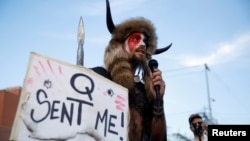 Sljedbenici teorija zavjere QAnona vjeruju da postoji zavjera elita koja dijabličnim planom želi da uništi svijet, dok se tajni spasilac ‘Q’ bori protiv njih. 