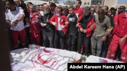 Persoane îndoliate, în jurul cadavrelor a opt membri ai Semilunii Roșii – recuperați la Rafah, la o săptămână după ce ar fi fost uciși de forțele israeliene și depuși într-o groapă comună.