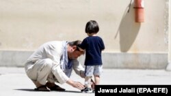 FILE: An Afghan man fixes his son's artificial leg frame received from ICRC's orthotopic center in Kabul.