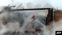 Pompier stingând incendiul la Prîluki, Ucraina, joi dimineață.