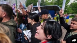 Olga mindenegyes hadifogolycserét igyekszik figyelemmel kísérni, és reméli, egyszer az ő férjét is szabadon engedik. A kép június 14-én készült, amikor egy hadifogolycsere keretében hazatérhettek Csernyihivbe orosz fogságba esett ukrán tengerészgyalogosok