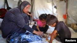 A lakóhelyüket elhagyni kényszerült palesztin nő gyermekeivel a sátrukban, Gáza városban, 2025. augusztus 1-jén