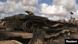 Čizma koja pripada vojniku lojalnom libijskom lideru Muameru Gadafiju i uništeni tenk, nakon vazdušnih napada od strane koalicionih snaga, na putu između Bengazija i Ajdabijaha, 21. mart 2011.