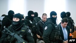 Marian Kocner (j) szlovák vállalkozót és Miroslav Marcek (k) bérgyilkost kísérik tavaly decemberben, a Ján Kuciak és jegyese, Martina Kušnírová meggyilkolása ügyében tartott tárgyalásra.