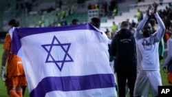Jucătorii echipei Maccabi Haifa cu steagul israelian la un meci internațional jucat la doar câteva săptămâni după atacul Hamas din 2023.