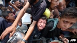 Copiii stau la coadă pentru mâncare la un punct de distribuție din Nuseirat, în centrul Fâșiei Gaza - 11 iunie 2025.