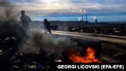 МАКЕДОНИЈА -- Луѓе кои собираат пластични шишиња на депонија поминуваат покрај отворен оган пред најголемата термоцентрала „РЕК БИТОЛА“ во близина на градот Битола. 