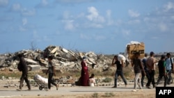 Палестинцы в секторе Газа с мешками и пустыми коробками бредут к пункту раздачи гумпомощи. 5 октября 2025 года