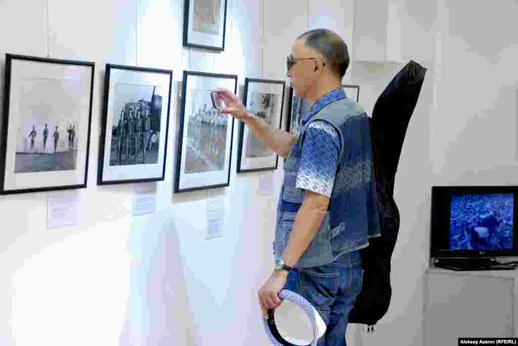 Посетитель выставки &laquo;Одна победа&raquo;, организованной посольством США, фотографирует увиденное на смартфоны.