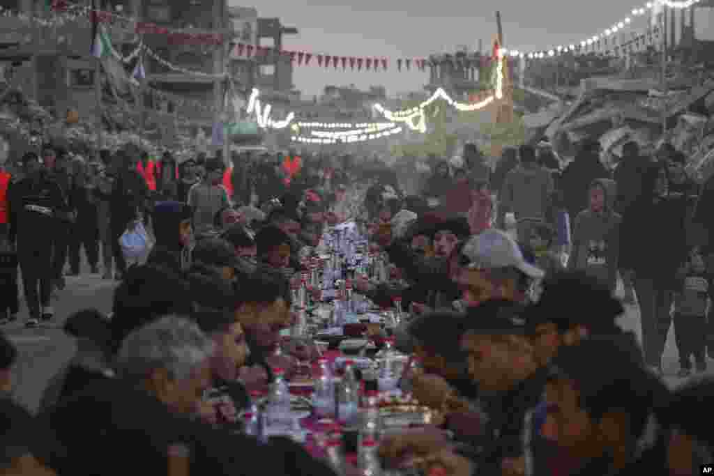Palestinezët e ulur në një tryezë të madhe për iftar, mes rrënojave të shtëpive dhe ndërtesave të shkatërruara në Rafah, në jug të Rripit të Gazës.