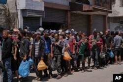 Grup de palestinieni la coadă pentru distribuirea de alimente în Deir al-Balah, Fâșia Gaza, 30 mai 2025.