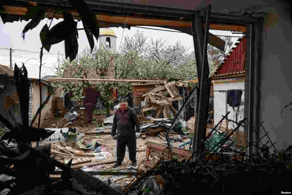 Житель Одессы стоит на заднем дворе своего дома, который был повреждён в результате удара российского дрона по украинскому портовому городу. Одесса, Украина, 16 апреля 2025 года. REUTERS/Nina Liashonok